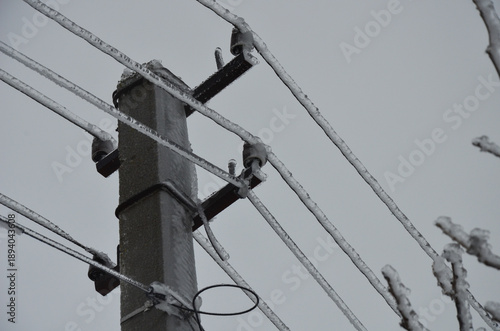 Power lines covered in thick ice after freezing rain. Risk of power outage. 