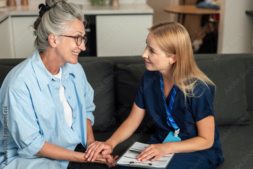 © brizmaker - Doctor visits elderly woman at home for health consultation and support © brizmaker - Doctor visits elderly woman at home for health consultation and support