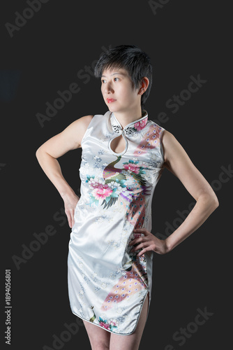 Chinese woman in short white patterned traditional dress staring to her right