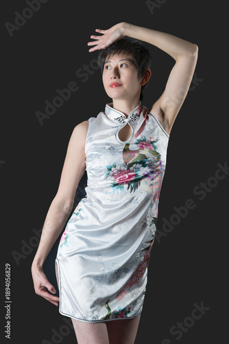 Chinese woman in white ftraditional dress one hand over head stares right