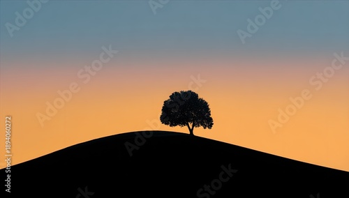 Silhouette of a lone tree atop a hill against an orange and blue gradient sky