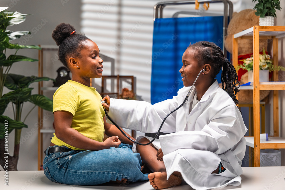 Obraz premium African girl children role-playing doctor and patient with stethoscope during pediatric visit in clinic