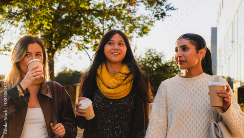 Diverse women friends walking together and drinking coffee cups during an afternoon outing
