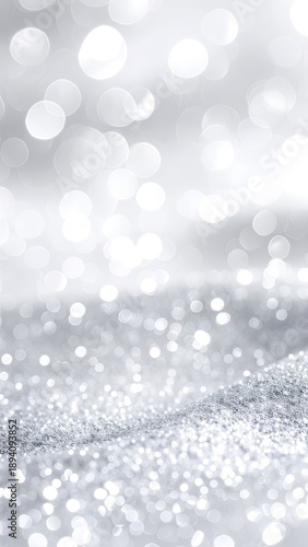 An abstract background featuring bright silver glitter and white bokeh lights for a festive or elegant feel.