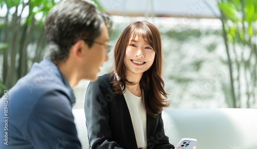 Foto ビジネスシーンで会話する男女, Business conversation between colleagues with smartphone in a br