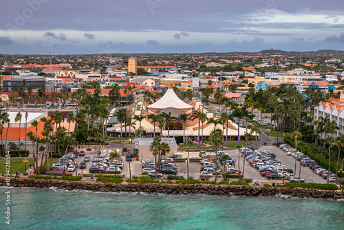 Panoramic view of Oranjestad, Aruba, showcasing colorful Dutch Caribbean architecture, palm trees, and waterfront with turquoise sea under dramatic evening sky
