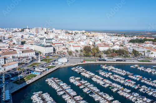 Visitors enjoy the marina view in Faro, Algarve, with boats docked and the old town visible under clear skies. This area attracts many tourists year-round