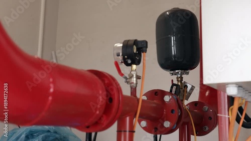 Expansion tank, Pressure gauge, Mechanical room. Close-up view expansion tank, gauge, and red industrial piping, likely part fire suppression or plumbing system.
