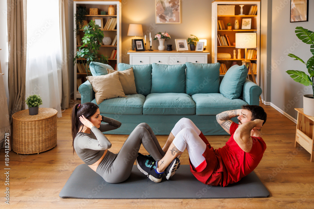 Obraz premium Couple doing sit ups while working out at home