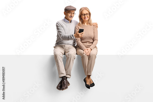 Mature couple sitting on a panel and looking at a smartphone together