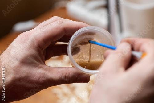 The master mixes the glue with the back of the brush