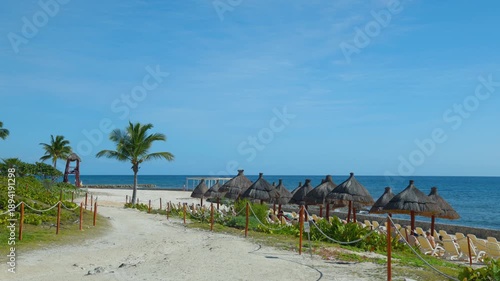 Beach Path with Lounge Chairs, Thatched Umbrellas, and Blue Ocean Under Clear Sky