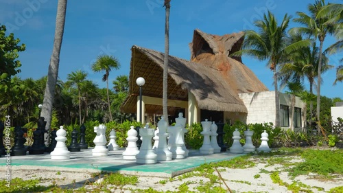 Giant Outdoor Chess Set in Front of Tropical Resort Building Under Blue Sky
