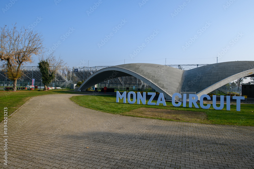 Fototapeta premium Iconic Monza Circuit entrance with modern curved architecture and bold signage, captured on a sunny day in Italy, symbolizing speed, motorsport heritage, and innovation.