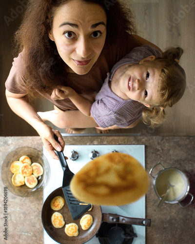 Mother cooking with a child. Multitasking life, parental leave, life with kids.