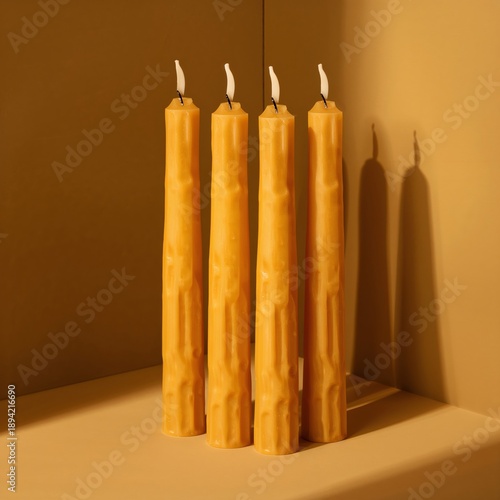 Three Candles Burn on a Plain Yellow Background in a Simple Setting During Da...