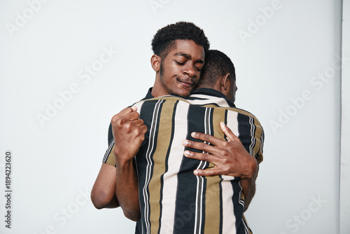 фотографія Two young black men hugging each other with eyes closed and peaceful expressions