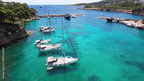 Cinematic Drone Flyover of Votsi Bay Alonissos — Sailing Boats Anchored in Turquoise Lagoon near Limestone Cliffs, Sporades Islands Greece