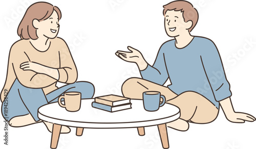 Friends chatting around a coffee table together, two people sitting comfortably with cups nearby and relaxed