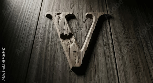 A wooden letter V centered on a dark wooden surface illuminated by a spotlight from above