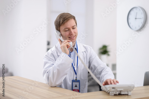 Foto Medical assistant answering phone at reception in clinic