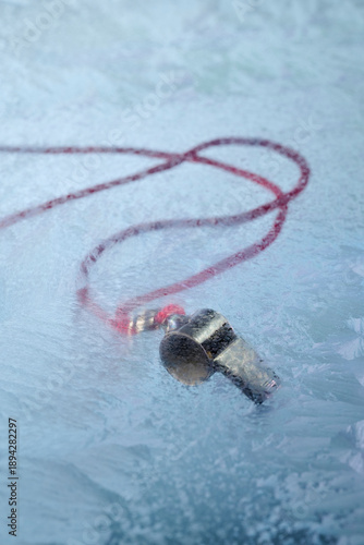 Whistle on lanyard under frozen sheet of ICE.  Social Editorial Commentary Silence 