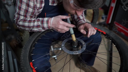 Professional mechanic in a workshop repairs a mountain bike, focusing on the hub and bearings. Wearing workwear, he provides expert service, lubrication, and maintenance to ensure smooth performance. 