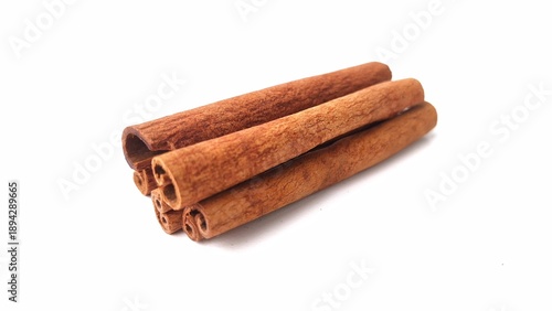 Cinnamon sticks (Cinnamomum verum) placed on a white background. They have a warm, reddish-brown hue and rough, textured surface. The sticks are tightly rolled, showcasing a cylindrical form