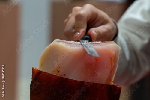 Schilderij op canvas Professional chef slicing Spanish Iberian pork jowl with a knife, showcasing exp
