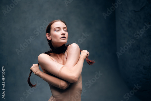Model poses in a studio wearing a fitted outfit with braids, showcasing confidence and strength in a creative art setting