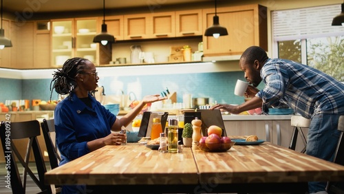 Canvas-taulu African american man in a hurry running late for his office job, skipping breakfast and leaving his housewife to eat alone at the table