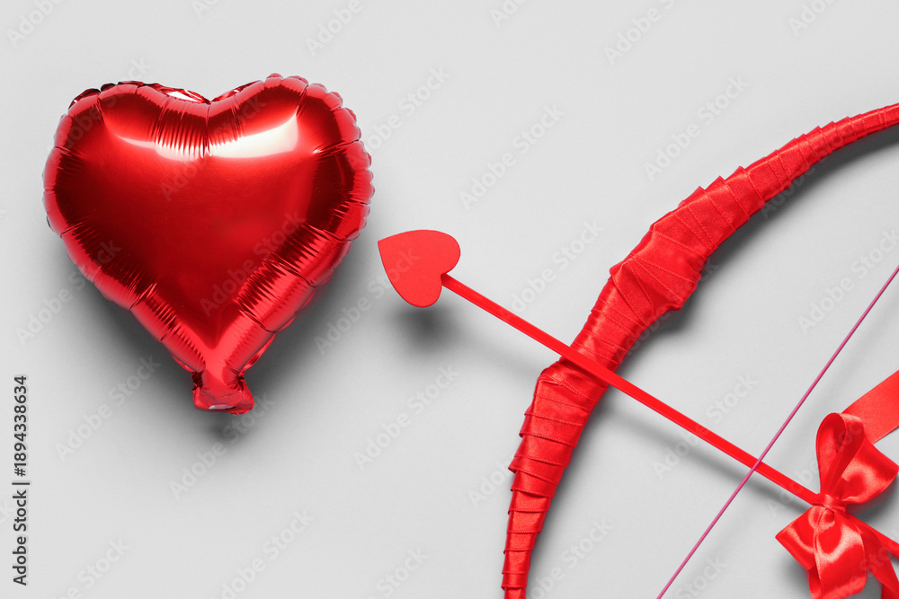 Fototapeta premium Cupid's bow and heart shaped balloon on grey background, closeup. Valentine's Day celebration