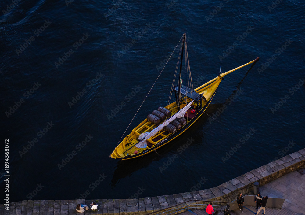 Fototapeta premium Small boat navigating dark blue water from a high angle.