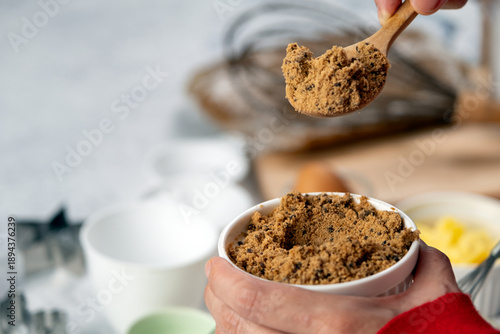 Wallpaper Mural Close-up of brown sugar in a ceramic bowl with a wooden spoon, prepared for baking with blurred kitchen tools in background, representing sweet ingredients and homemade cooking Torontodigital.ca