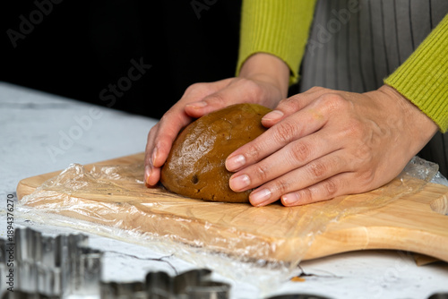 Wallpaper Mural Close-up of hands kneading cookie dough on a wooden cutting board with plastic wrap, preparing homemade baked goods in a cozy kitchen Torontodigital.ca