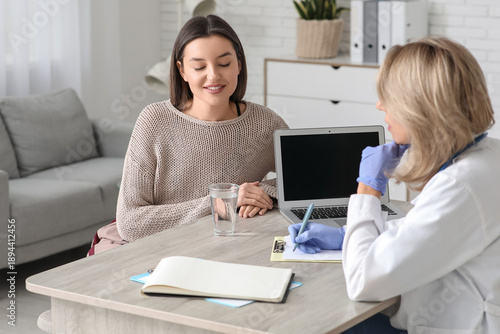 Young woman visiting doctor at table in clinic