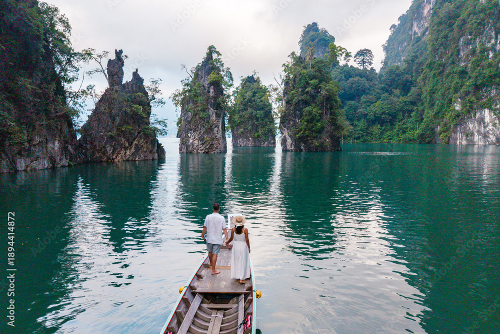 Fototapeta premium Couple exploring stunning limestone cliffs in Khao Sok National Park during peaceful boat ride