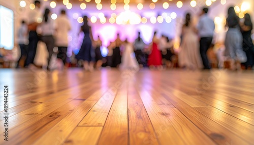 Blurred background of people dancing on a wooden floor at a vibrant party or wedding reception.