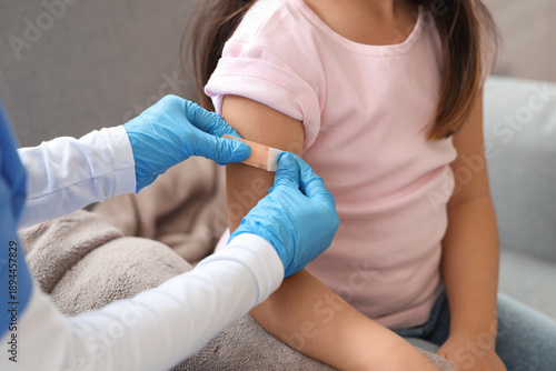 Obraz na plátne Little girl applying medical patch after vaccination in clinic, closeup