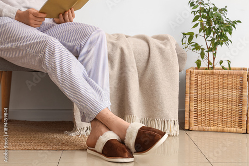 Man with book in slippers s...