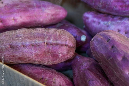 Large purple sweet potatoes at a popular Asian market. Healthy vegetarian food. Close-up.