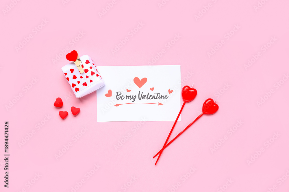 Fototapeta premium Composition with greeting card, gift box and candles for Valentine's Day celebration on pink background