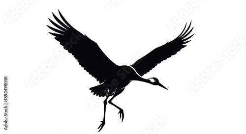 Dynamic black silhouette of a Japanese crane or heron landing with its wings spread wide and legs extended downwards.