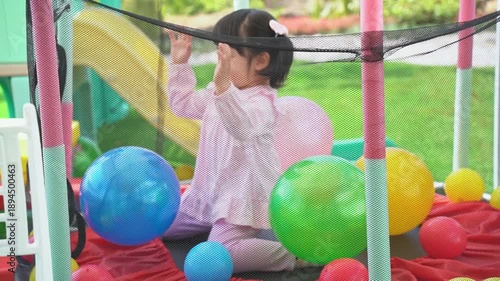 Joyful Toddler Playing in Colorful Ball Pit Surrounded by Bright Balls on a Sunny Day in a Playful Backyard Environment