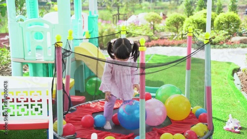 Happy Child Playing in Colorful Ball Pit Surrounded by Play Equipment in Bright Outdoor Playground Setting on a Sunny Day