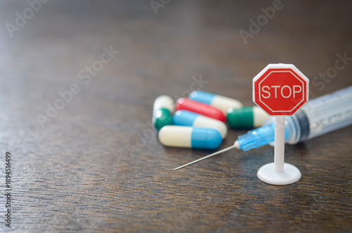 Фотография "Colorful Capsules with Syringe and STOP Sign Symbolizing Drug Caution and Medic
