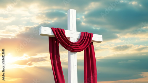 A white cross with red cloth draped over it stands against a cloudy sky at sunset