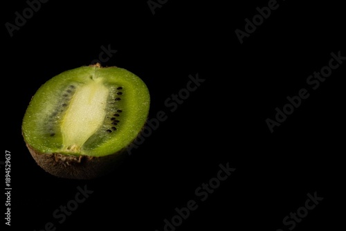 Fresh green kiwi fruit halves on a black background