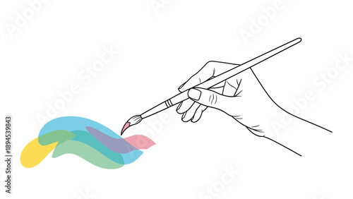 Close up of a hand holding a paintbrush and applying colorful strokes of blue, green, and pink paint on a white surface.