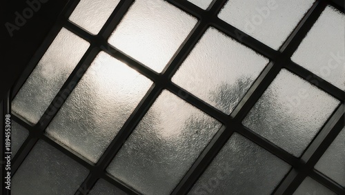 Sunlit, frosted glass window panes. Dark interior, hazy view